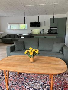 sala de estar con sofá y mesa con flores amarillas en Randbøldal Camping & Cabins, en Randbøl