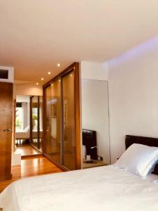 1 dormitorio con cama blanca y pared de cristal en Apartamento Exclusivo a pie de Playa en Vigo