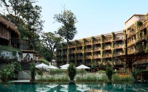 Dinso Resort & Villas Phuket, Vignette Collection, an IHG Hotel في شاطيء باتونغ: مبنى كبير فيه مظلات امام المسبح