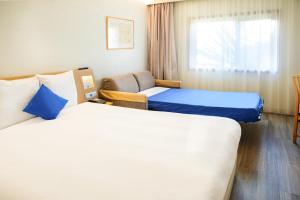 a hotel room with two beds and a chair at Novotel Porto Gaia in Vila Nova de Gaia