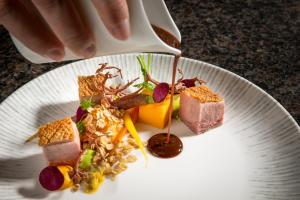 un piatto di cibo con una persona che versa la salsa di Hotel Auenhof a Lech am Arlberg