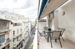 een balkon met een tafel en stoelen in een stadsstraat bij YestayHomes * Kolonaki * Tsakalof Street in Athene