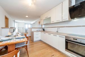 a kitchen with white cabinets and a wooden table at Ema's Olive Garden Apt 2 -private parking, 10 min drive from sandy beach in Poličnik