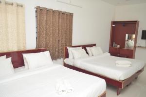 2 camas en una habitación con sábanas blancas en JP Homes, en Yercaud