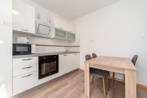 a kitchen with white cabinets and a wooden table at Ema's Olive Garden Apt 1 with private parking, just 10 minutes drive from sandy beach in Poličnik +21 photos