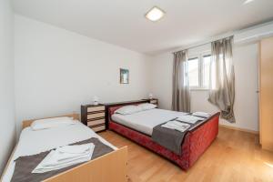 a bedroom with two beds and a window at Ema's Olive Garden Apt 1 with private parking, just 10 minutes drive from sandy beach in Poličnik