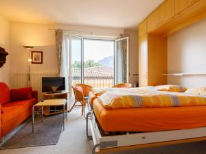 a bedroom with a bed and a couch and a television at Apartment Residenza Corallo-10 by Interhome in Ascona +11 photos