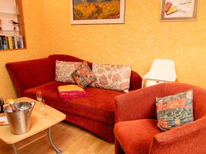 ノルデンにあるHoliday Home Schäfer by Interhomeのリビングルーム(赤いソファ、椅子2脚付)
