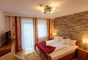 a bedroom with a large bed and a brick wall at Hotel Kärntnerhof & SeeBlick Suiten in Lake Pressegg