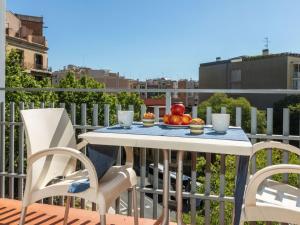 a table and chairs on a balcony with a bowl of fruit at Apartment Eixample Esq Rocafort Diputacio by Interhome in Barcelona