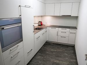 uma cozinha branca com armários brancos e um lavatório em Apartment Apt B 022 by Interhome em Disentis