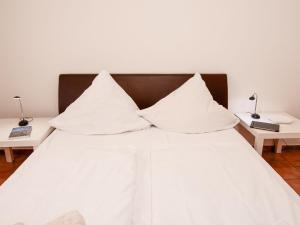 - un lit blanc avec des oreillers blancs et 2 tables dans l'établissement Apartment Teetied by Interhome, à Norddeich