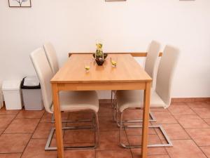 - une table en bois avec des chaises blanches et un vase dans l'établissement Apartment Teetied by Interhome, à Norddeich
