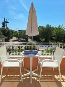un tavolo da patio con sedie e ombrellone sul balcone di The Red Dragon a Dassia