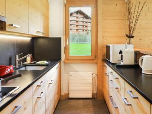 una cocina con armarios de madera y encimeras negras en Apartment Diamant 6 by Interhome, en Villars-sur-Ollon