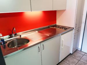 a kitchen with a sink and a red wall at Apartment Apt B 057 by Interhome in Disentis