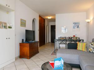uma sala de estar com um sofá e uma televisão em Apartment Miralago - Utoring-24 by Interhome em Piazzogna