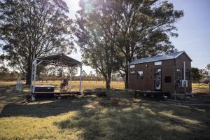 un hombre de pie junto a una casa pequeña en Odyssean Tiny House B, en Cessnock