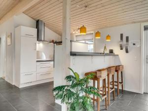 a kitchen with white cabinets and a bar with stools at Holiday Home Fabio - 450m from the sea in NW Jutland by Interhome in Løkken