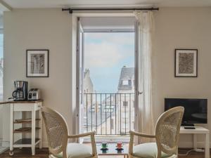 a room with a window with chairs and a television at Apartment L'Anse by Interhome in Dinard