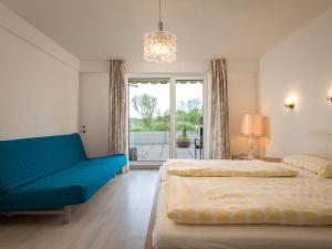 een slaapkamer met 2 bedden en een blauwe bank bij Apartment Terrassenwohnung am Kurpark by Interhome in Lahnstein