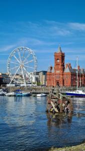 a ferris wheel in front of a building with a clock tower at Flat 2, Close to all amenities Shared bathroom in Cardiff