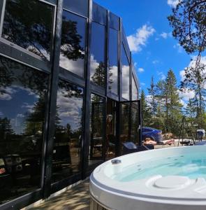 un gran edificio de cristal con bañera de hidromasaje frente a él en Ekornredet (The Squirrel Nest), en Kongsberg