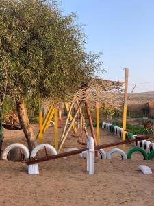 un parque infantil con columpios y un árbol en Coparc 