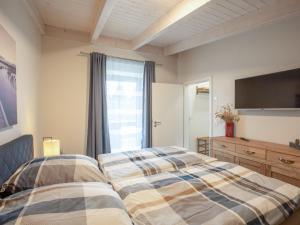 a bedroom with a bed and a flat screen tv at Apartment Nachtigall II-2 by Interhome in Osten