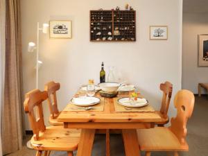 uma mesa de madeira com 2 cadeiras e uma garrafa de vinho em Apartment Chalet Simmental P-3 by Interhome em Zweisimmen