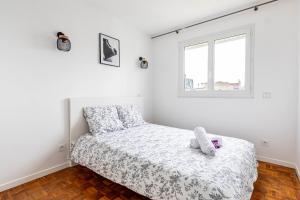 um quarto branco com uma cama e uma janela em 2 pièces, calme et lumineux. em Boulogne-Billancourt