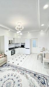 une cuisine avec des armoires blanches, une table et un tapis dans l'établissement # 51 Светлая квартира в ЖК Лагуна, à Atyraū