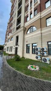 un bâtiment avec un parterre de fleurs devant dans l'établissement # 51 Светлая квартира в ЖК Лагуна, à Atyraū