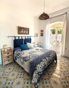 Schlafzimmer mit einem blauen und weißen Bett und einem Fenster in der Unterkunft Mediterranea Casa del Capricorno in Massa Lubrense