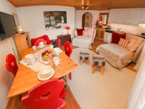 Apartment Marie-Soleil Est by Interhome في غشتاد: غرفة معيشة مع طاولة خشبية وكراسي حمراء