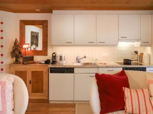 uma cozinha com armários brancos e uma almofada vermelha em Apartment Marie-Soleil Est by Interhome em Gstaad