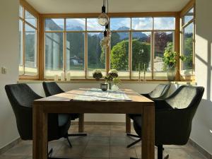 a dining room table with black chairs and windows at Ferienwohnung Marianne Bergpanorama für Paare 60qm in Berchtesgaden