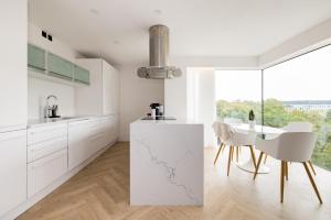 una cucina con armadi bianchi, tavolo e sedie di Modern, Luxury 2-Bed Home with Private Balcony a Londra