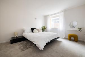 een witte slaapkamer met een bed en een raam bij Modern, Luxury 2-Bed Home with Private Balcony in Londen