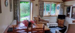 a living room with a table and a couch and windows at Granite Croft in Appin