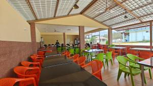 奇克马格尔Rangi Taranga Resort的一家有桌椅和背景人物的餐厅