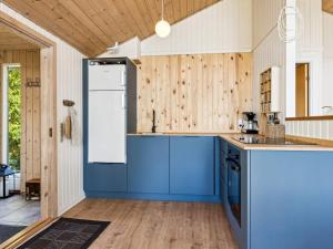 a kitchen with blue cabinets and wooden walls at Holiday Home Anne - 150m from the sea in SE Jutland by Interhome in Børkop