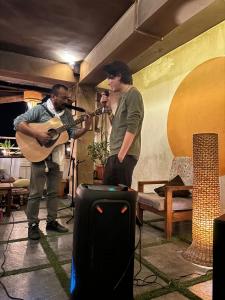 two men in a room with a guitar and a guitarist at Mellow Fellow Hostel in Gangtok