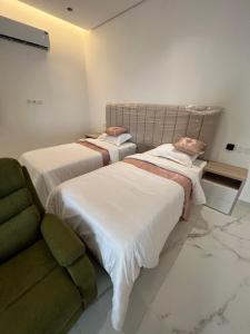 2 camas en una habitación con sofá en سرايا الخليجية, en Al Hofuf