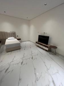 biały pokój z łóżkiem i telewizorem w obiekcie سرايا الخليجية w mieście Al-Hufuf