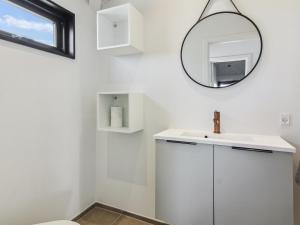 een witte badkamer met een wastafel en een spiegel bij Holiday Home Månviva - 500m from the sea in NW Jutland by Interhome in Løkken