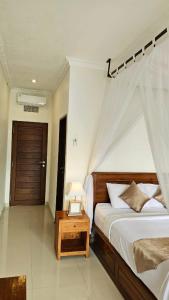 a bedroom with a bed and a table with a lamp at Nadya Homestay in Munduk