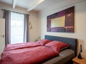 a bedroom with a bed with red sheets and a window at Apartment Nachtigall II-3 by Interhome in Osten