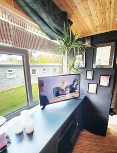 a desk with a tv on a wall with a window at 18 Bucklands - Cosy 5-Star Chalet - Starlink Wi-Fi - Coastal Woodland in Bucks Mills