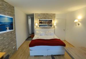 a bedroom with a large white bed with red blanket at Hotel Kärntnerhof & SeeBlick Suiten in Presseggersee